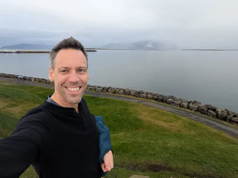 Nathan smiling beside the Reykjavík harbour shoreline